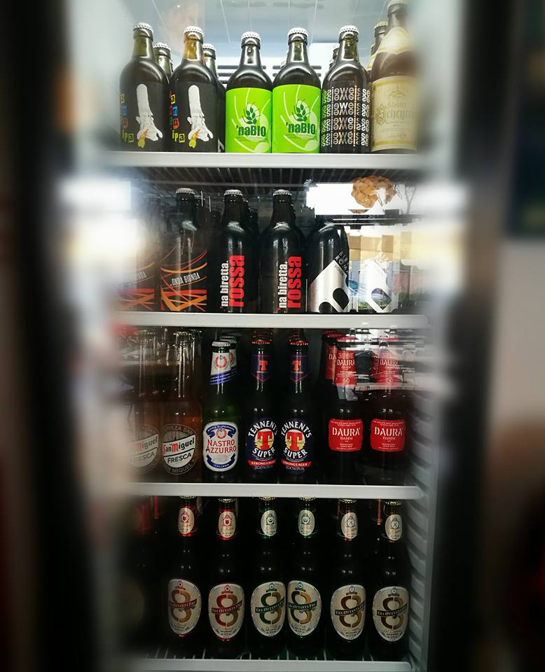 Un espositore refrigerato pieno di bevande in bottiglia di vario tipo disposte sugli scaffali.