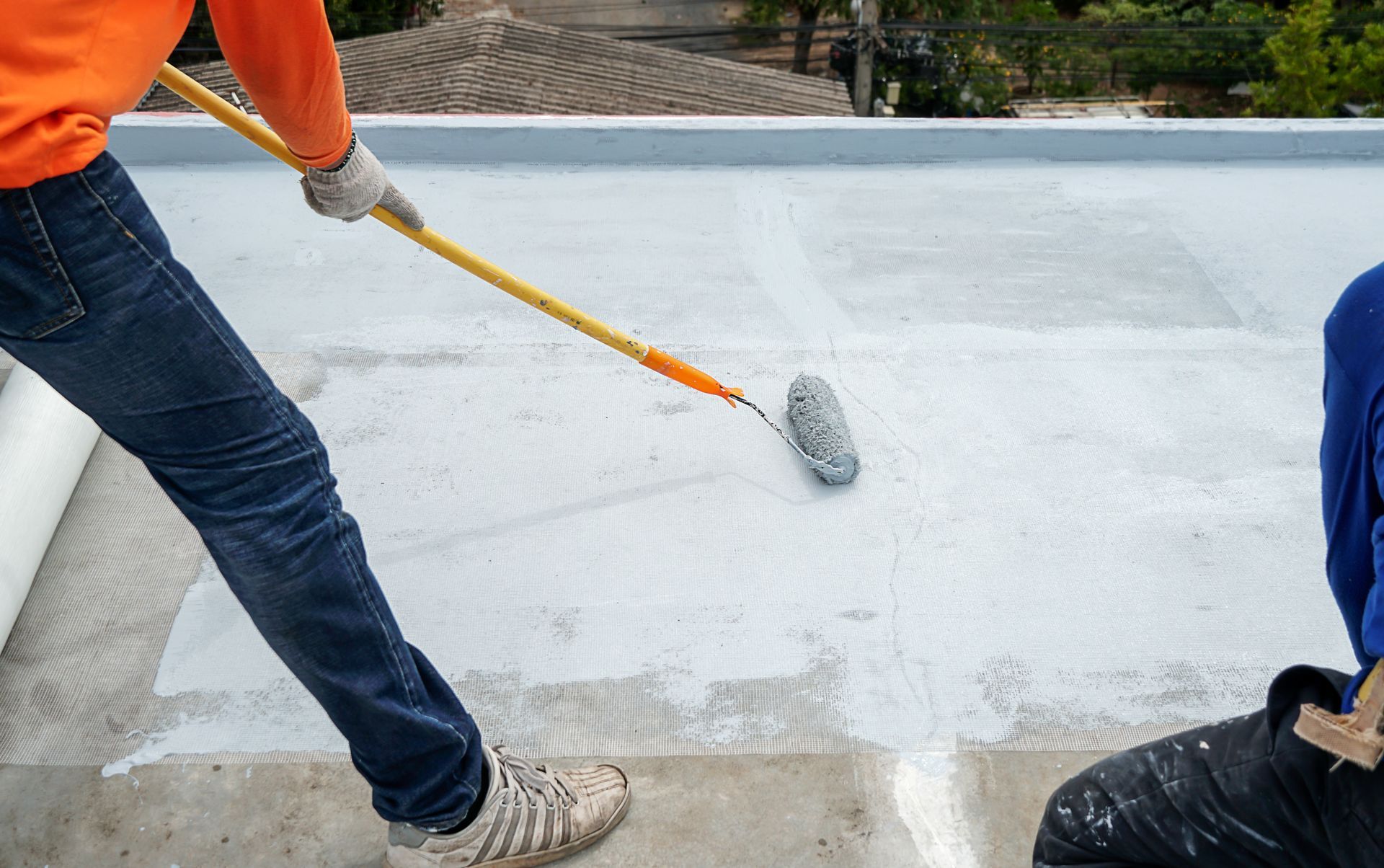 A man is painting a roof with a roller.