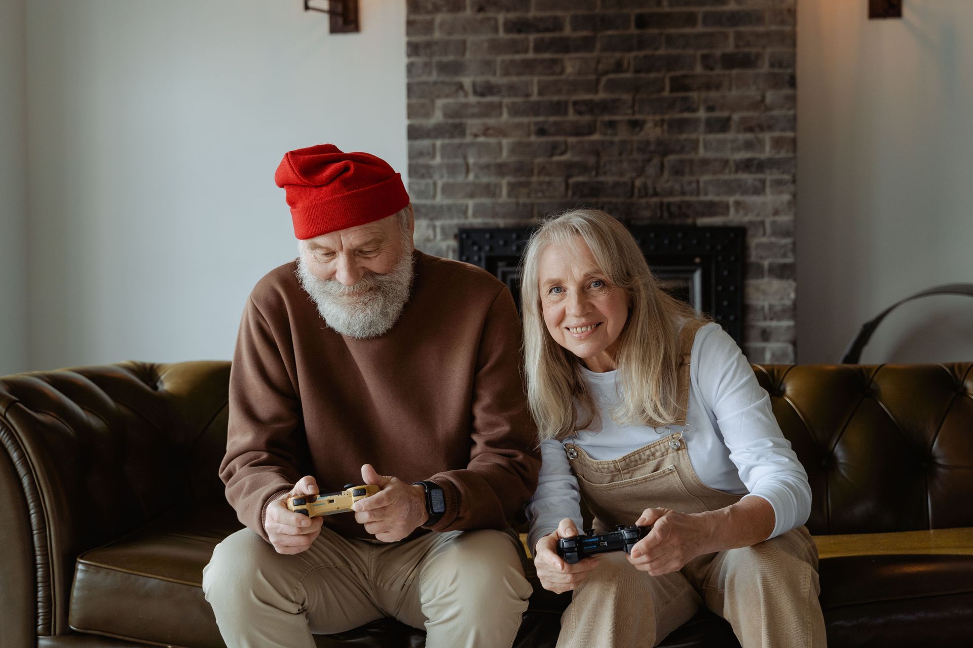 Couple sitting on a couch playing video games in a cozy living room with a brick fireplace.