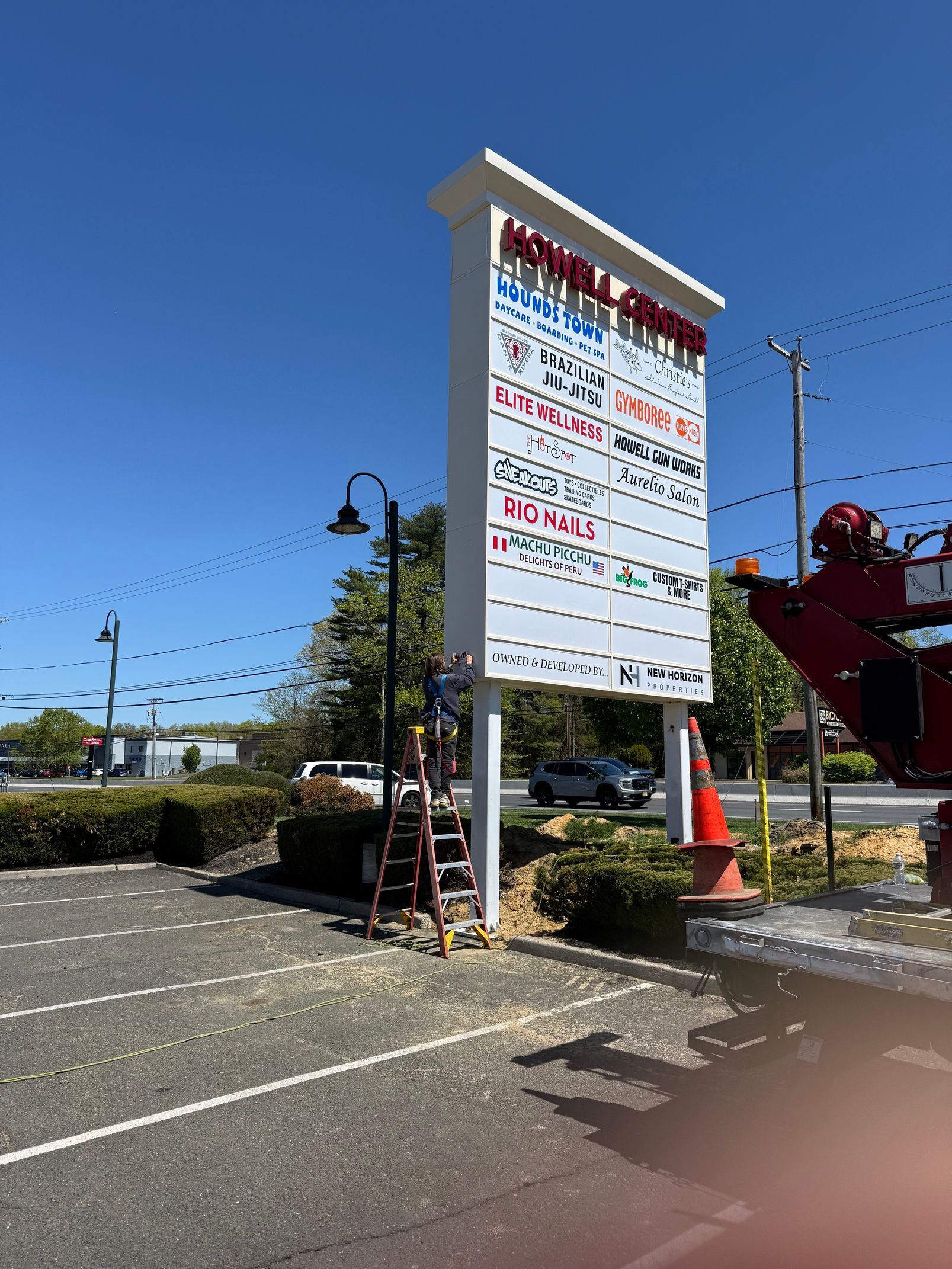 Tall roadside signboard with Japanese text beside a parking lot under a clear blue sky