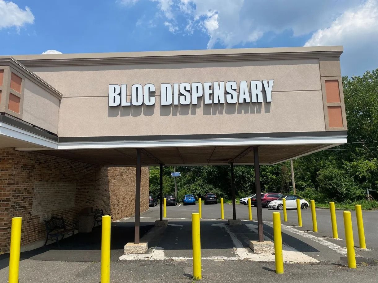 Bloc Dispensary storefront with covered drive-thru and yellow bollards under a cloudy sky