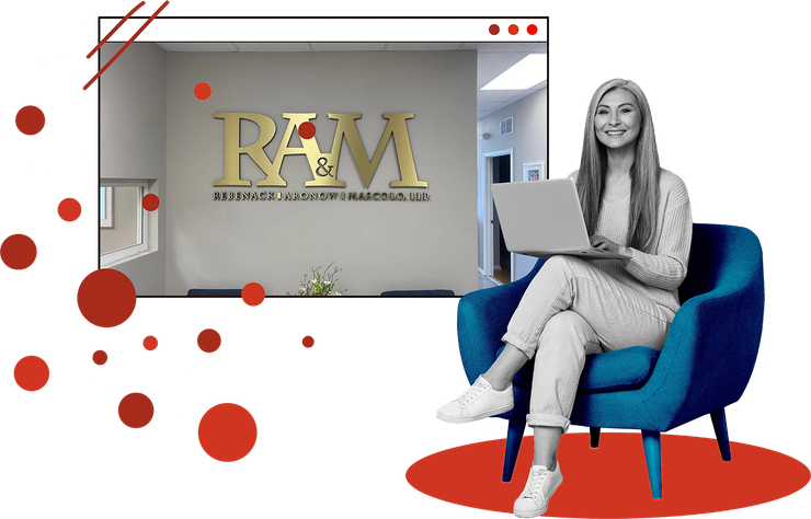 Woman using laptop in blue chair beside a R&M office logo display with red accents