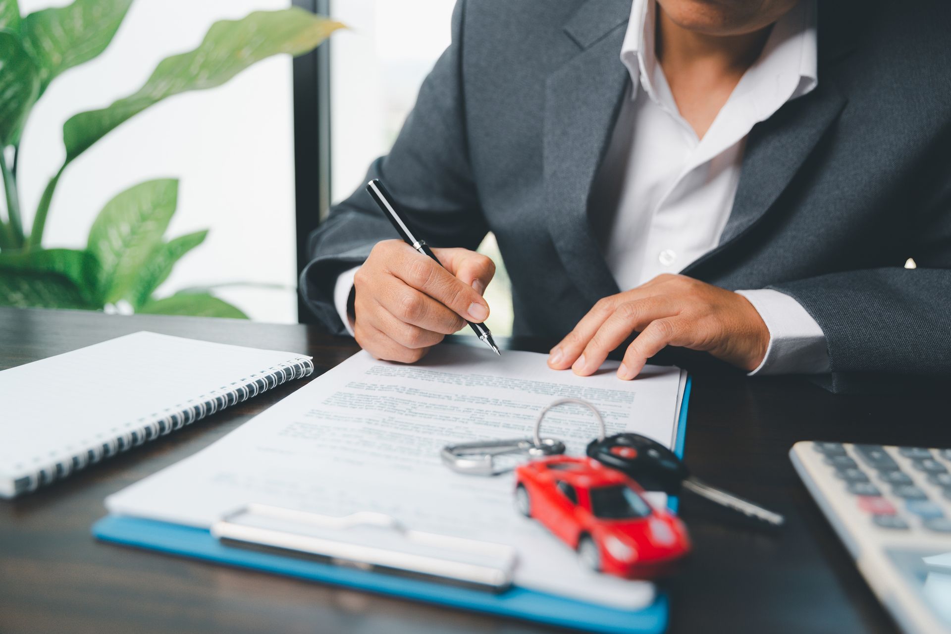 An agent in a suit, from an auto insurance agency, is working on insurance documents.