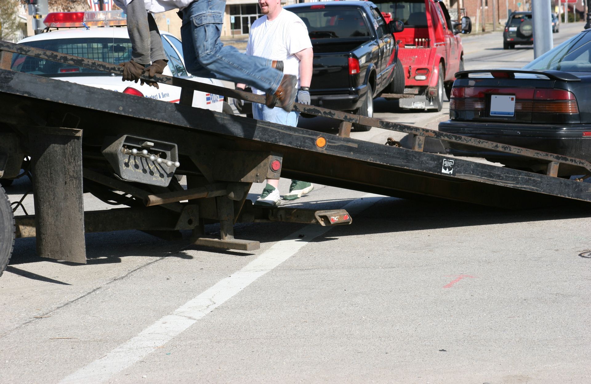 Tow truck loading damaged car after accident on urban street with multiple vehicles.