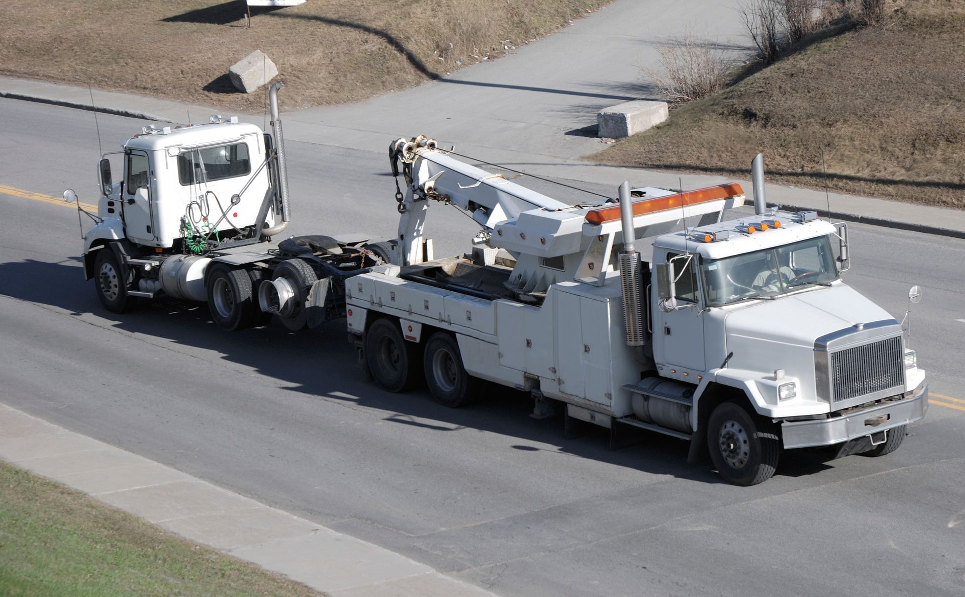 A big semi-truck is being towed by a heavy tow truck.