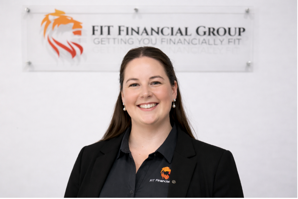 Woman smiling in front of a FIT Financial Group sign featuring a lion logo — Fit Financial Group in Leumeah, NSW