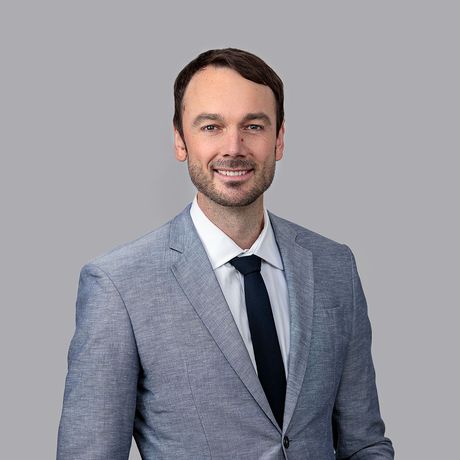 A man in a suit and tie is standing in front of a brick wall.