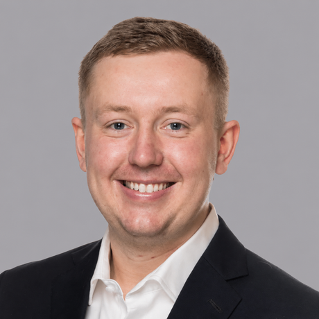 A man in a suit and tie is smiling for the camera