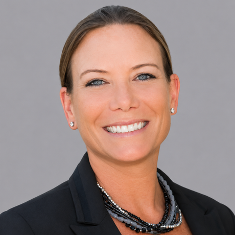 A woman is smiling in front of a brick wall