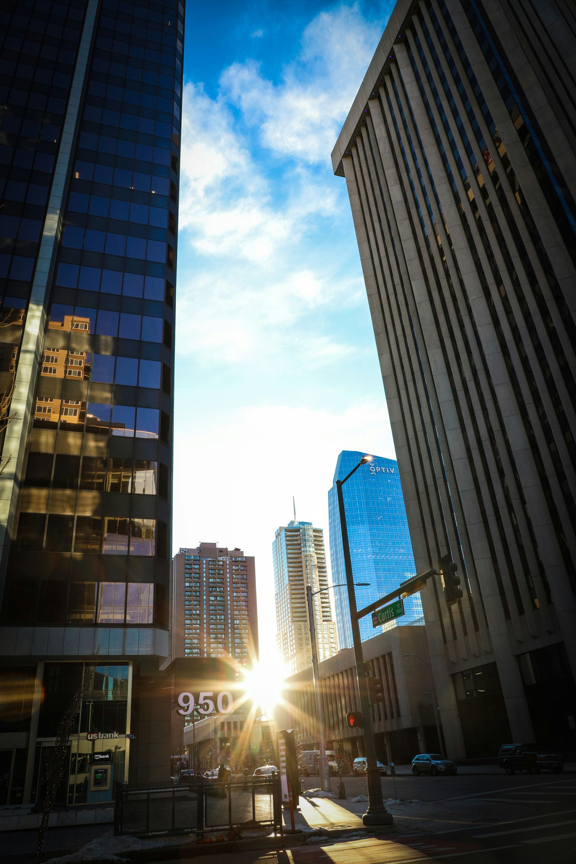 The sun is shining through the windows of tall buildings in a city.