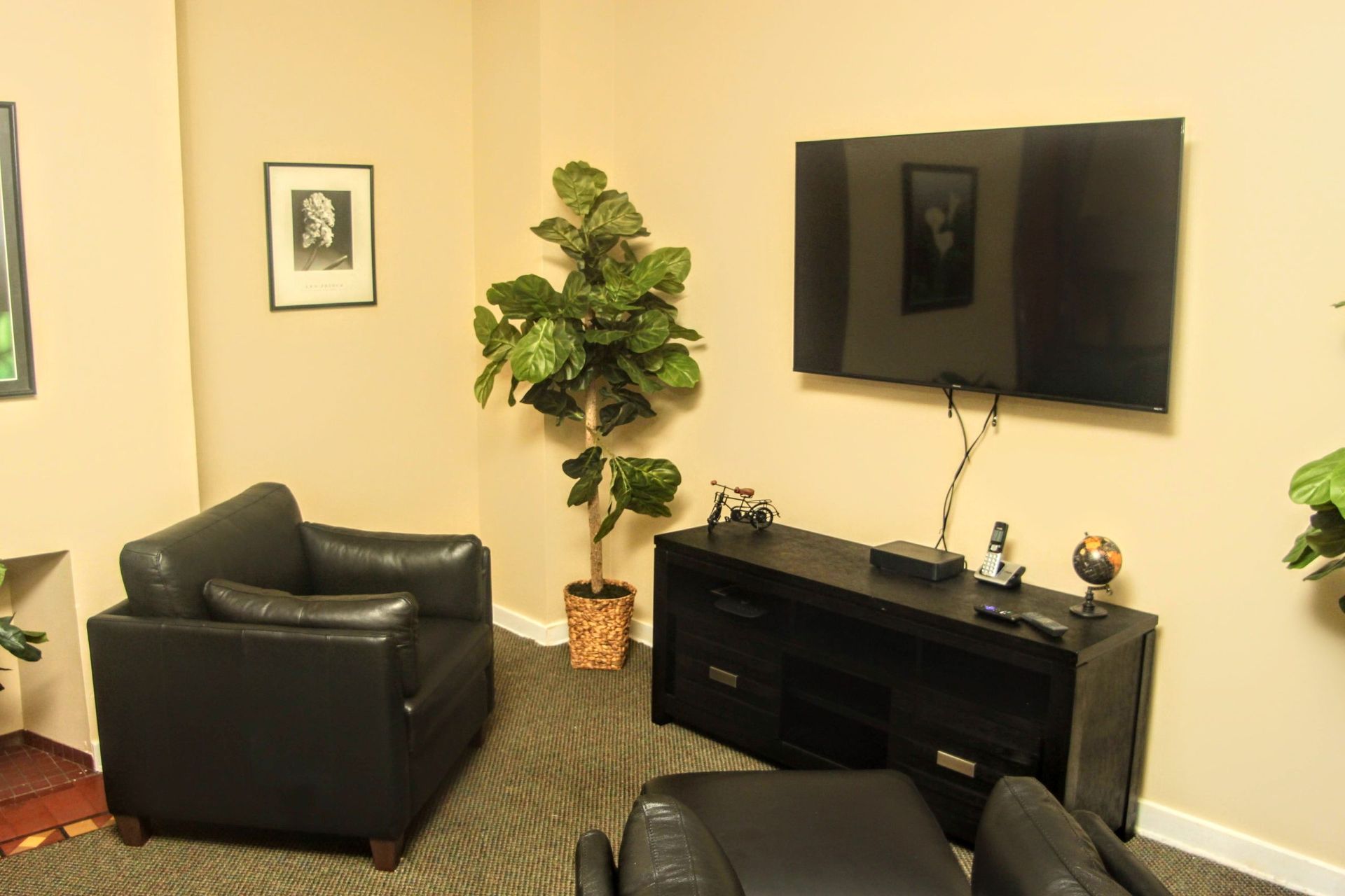 A living room with two black chairs and a flat screen tv