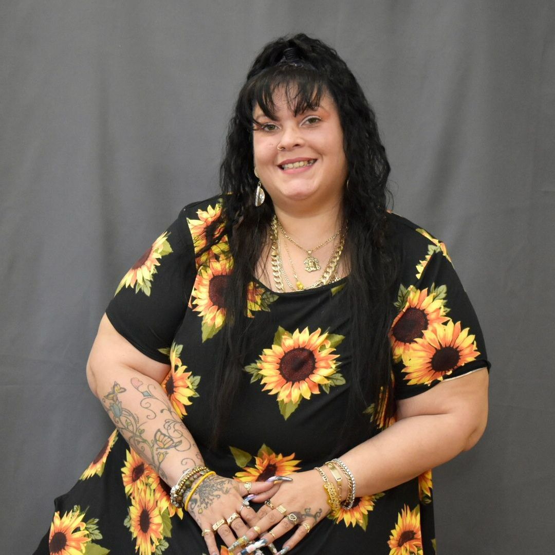A woman wearing a black dress with sunflowers on it