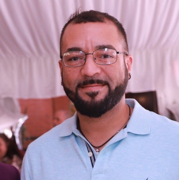 A man with a beard wearing glasses and a light blue shirt