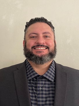 A man with a beard and a suit is smiling for the camera.