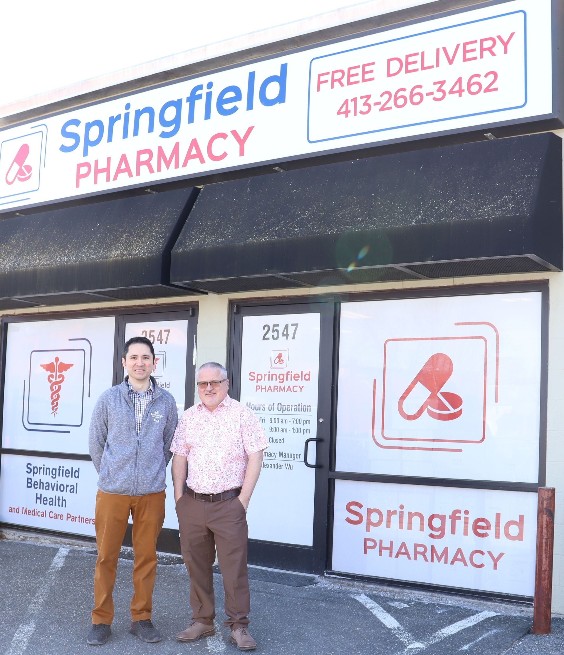 Two men are standing in front of Springfield Pharmacy