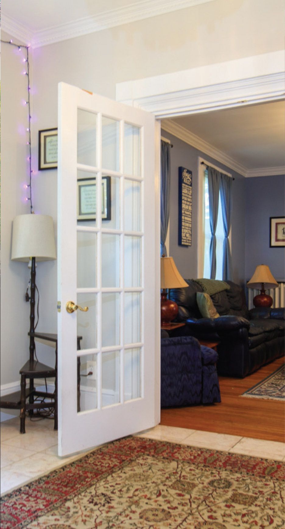 A living room with a french door open and a rug on the floor
