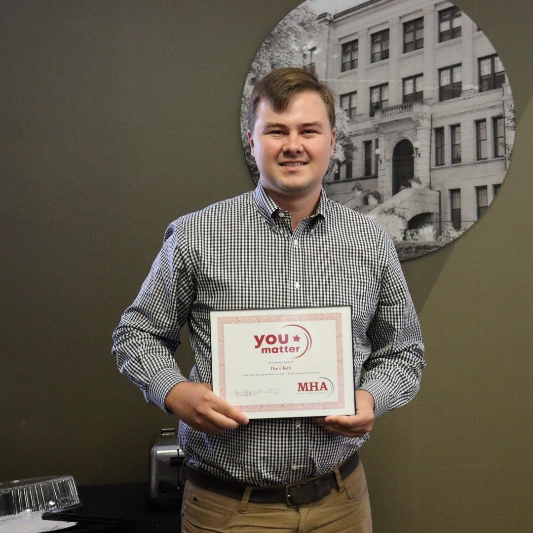 A man in a plaid shirt is holding a certificate.