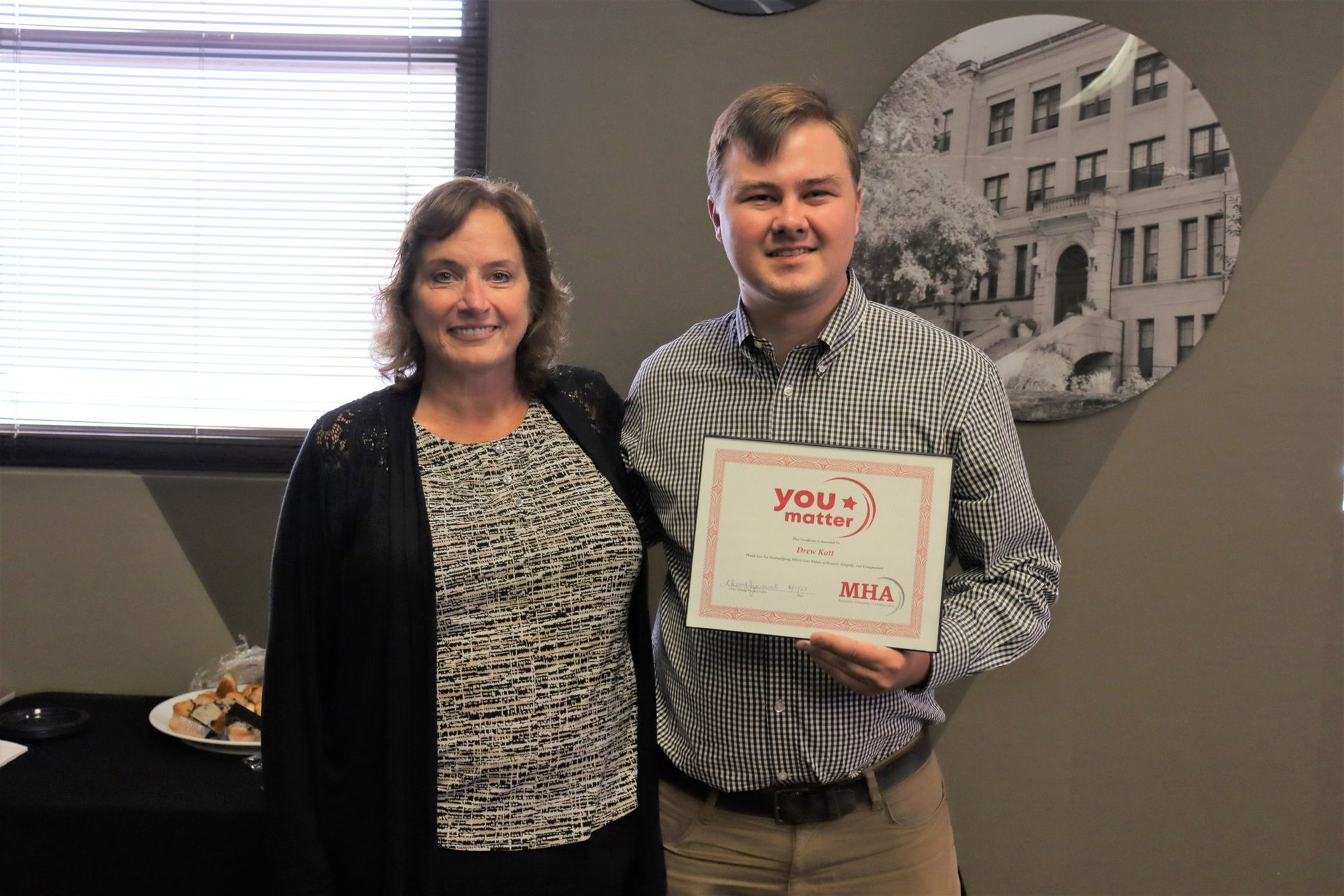 A man and a woman are standing next to each other holding a certificate.