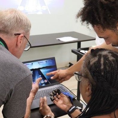 A group of people are looking at a laptop computer using the Music Glove technology