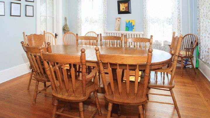 A dining room with a large wooden table and chairs.