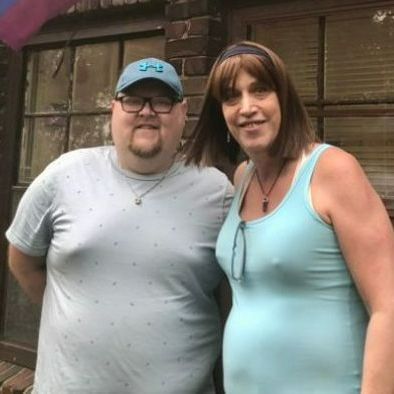 A man and a woman are posing for a picture in front of a building.