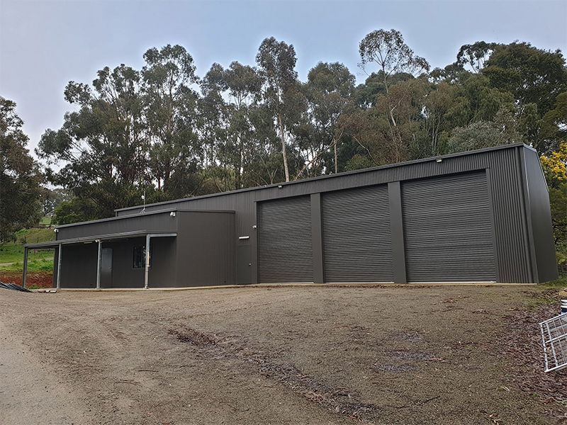 A large building with a lot of garage doors is surrounded by trees.