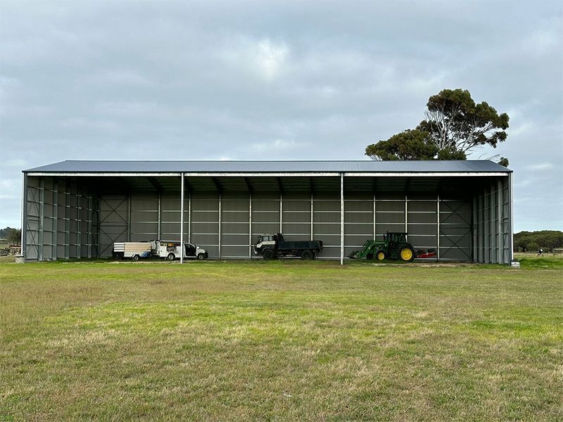 A tractor is parked in front of a building in a field.