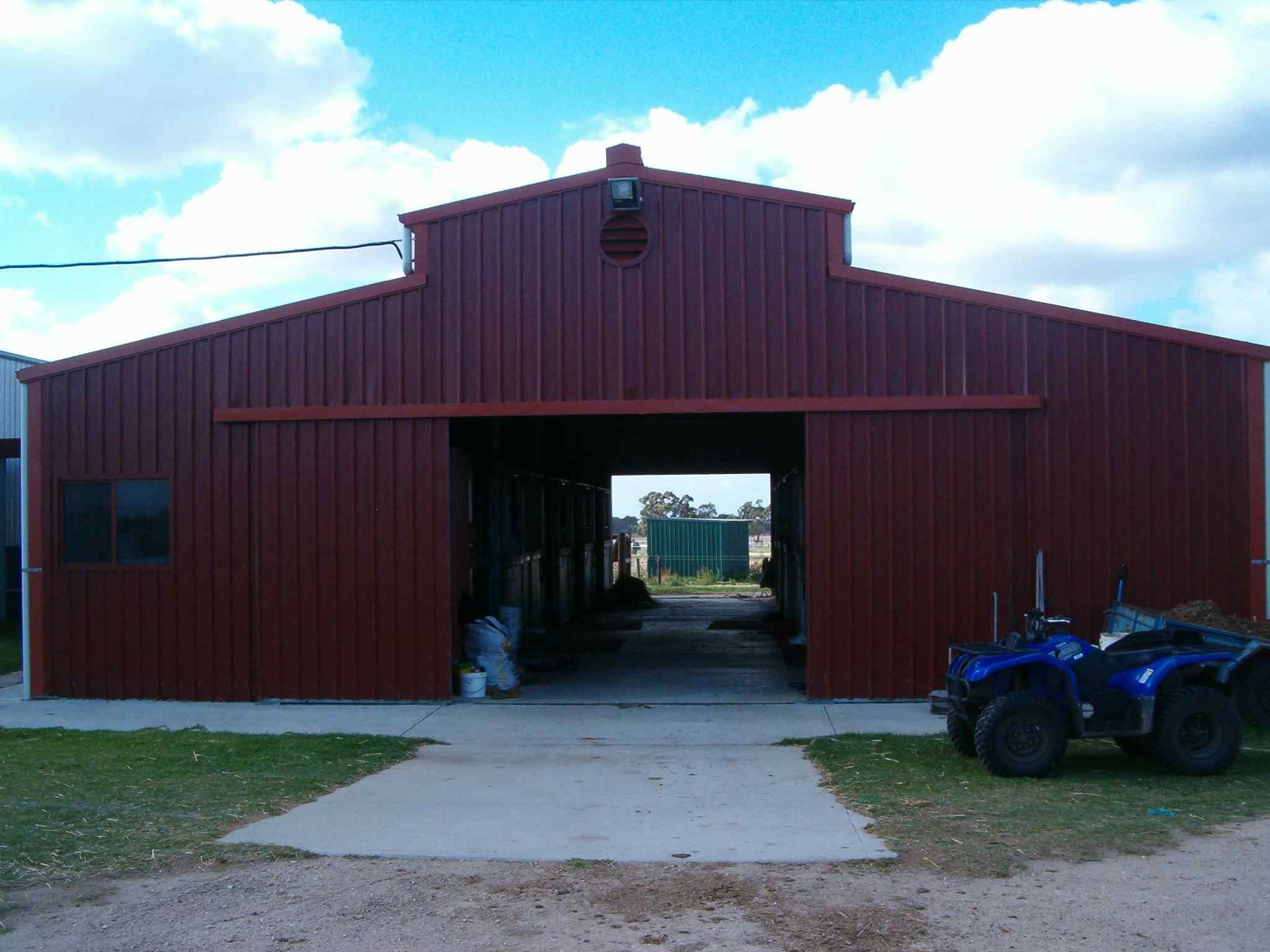 A red barn with a blue atv parked in front of it