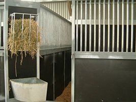 There is a hay bale in the corner of a stable.