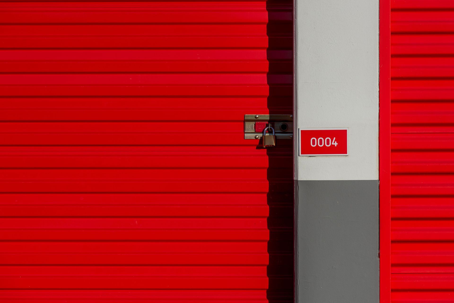 Red roll-up doors at a self-storage facility — conditioned units keep furniture safe while the crews work