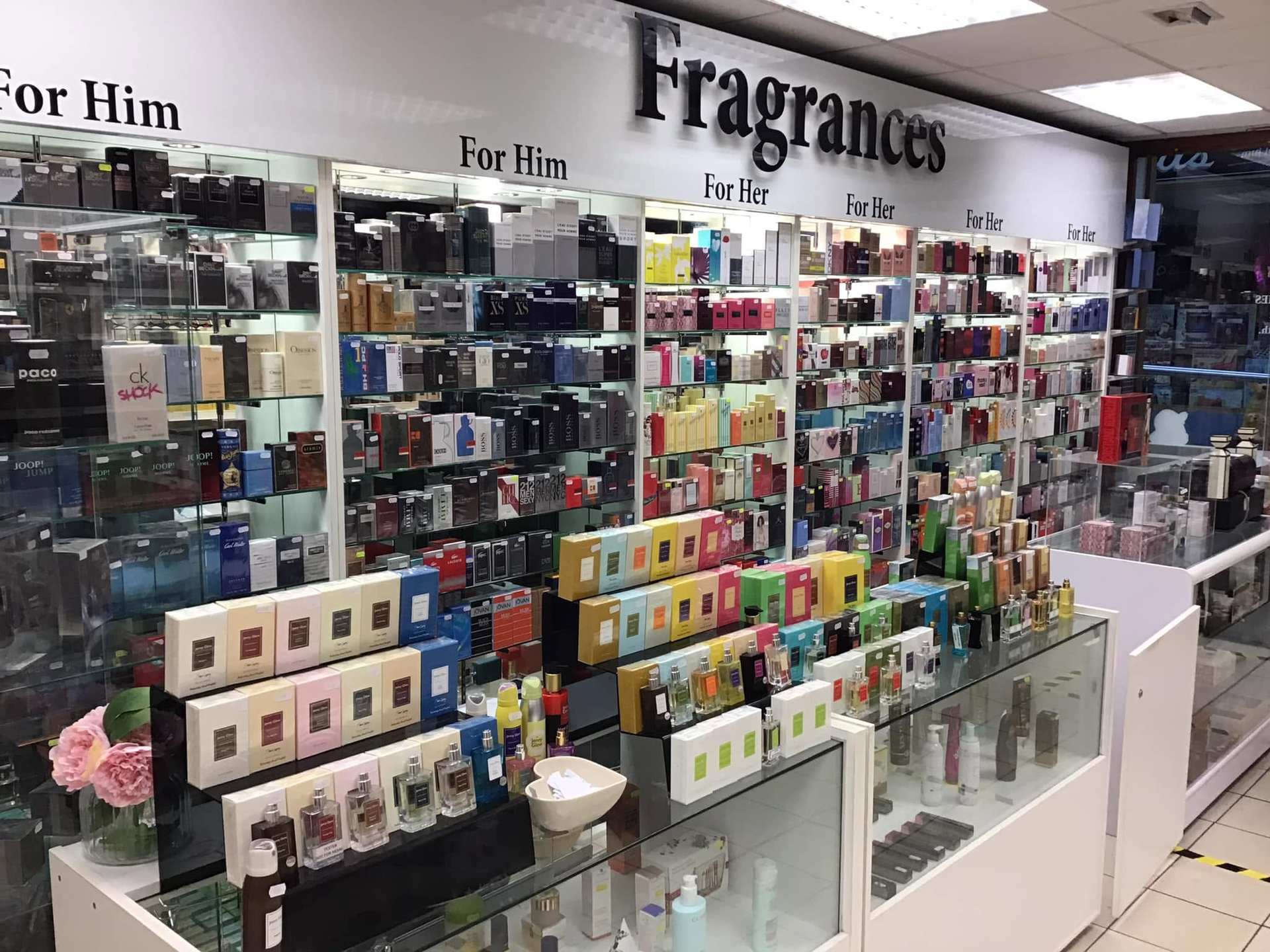 Perfume display counter with rows of colorful fragrance bottles in a store