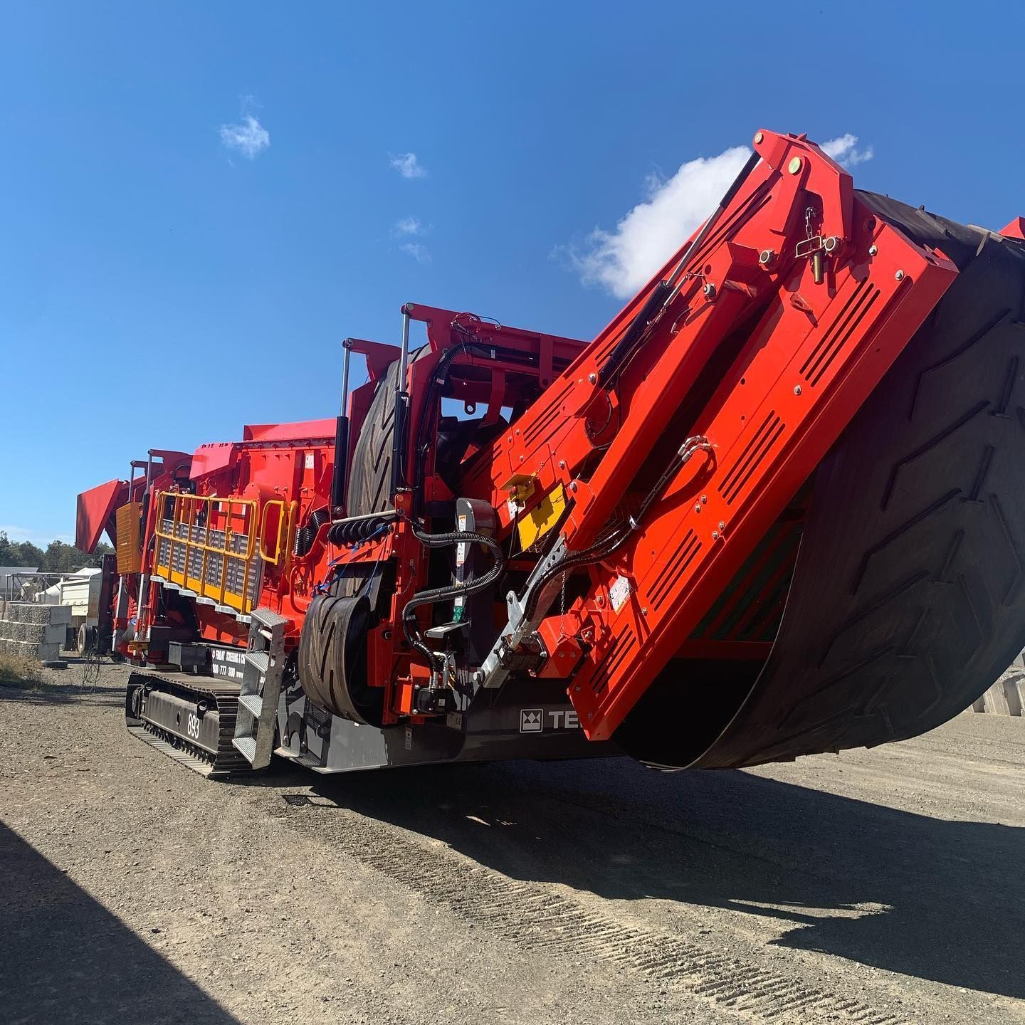 Red Tracked Rock Crusher Machine on Gravel with Blue Sky Background — Barlow's Earthmoving in Yeppoon, QLD