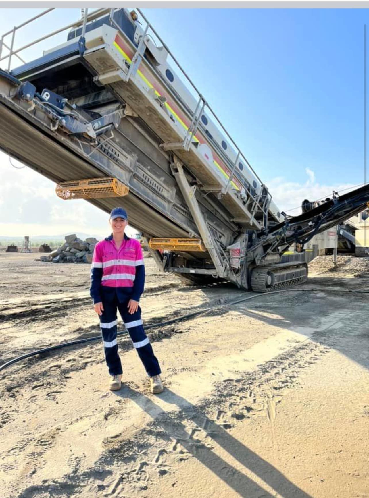 Woman in Work Clothes Standing Near a Large Industrial Machine in A Gravel Pit — Barlow's Earthmoving in Emu Park, QLD