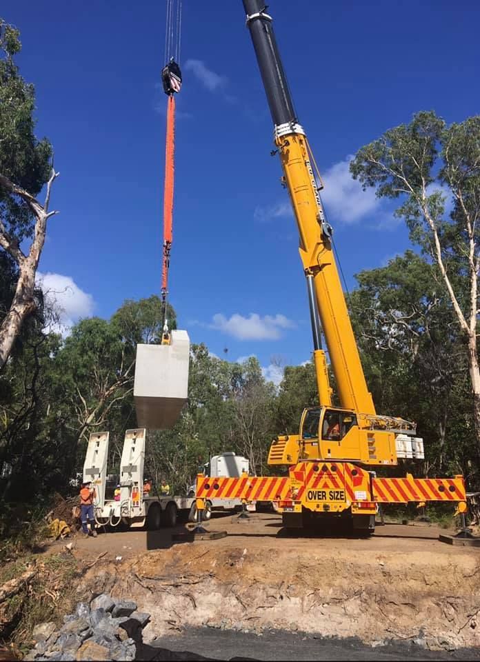 Yellow Crane Lifting a Concrete Box in A Wooded Area Under a Blue Sky — Barlow's Earthmoving in Emu Park, QLD