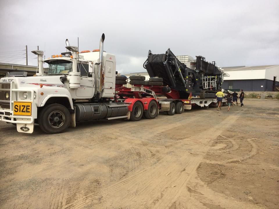 White Semi-Truck Transporting Large Machinery on A Flatbed Trailer — Barlow's Earthmoving in Emu Park, QLD