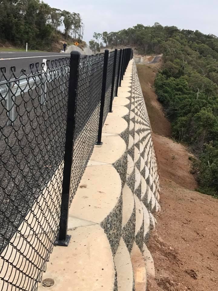 Black Chain-Link Fence on Concrete Wall with Geometric Design — Barlow's Earthmoving in Coorooman, QLD