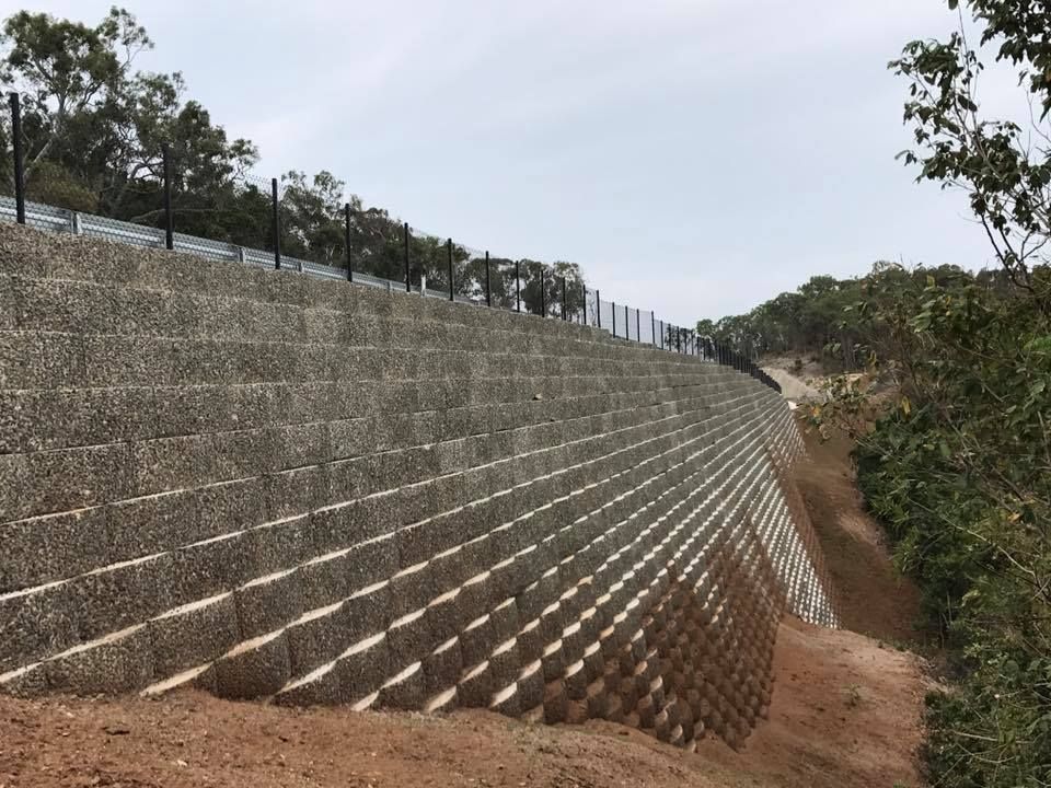 A Large, Gray Retaining Wall Built Into a Hillside — Barlow's Earthmoving in Coorooman, QLD