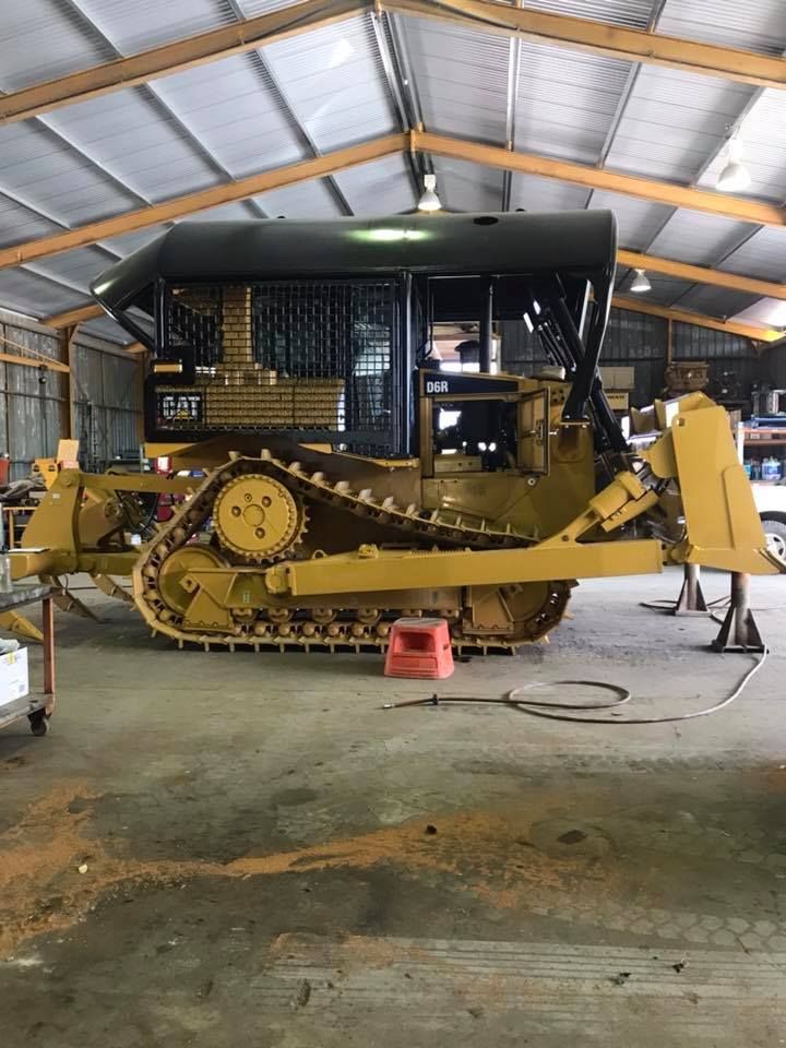 Yellow Caterpillar Bulldozer Inside a Workshop, with Black Protective Cabin — Barlow's Earthmoving in Gladstone, QLD