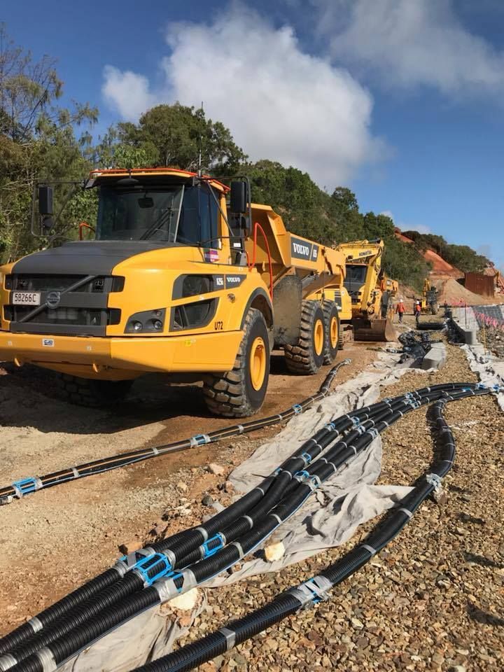 Yellow Construction Vehicles Beside Black Cables on A Gravel Road — Barlow's Earthmoving in Coorooman, QLD