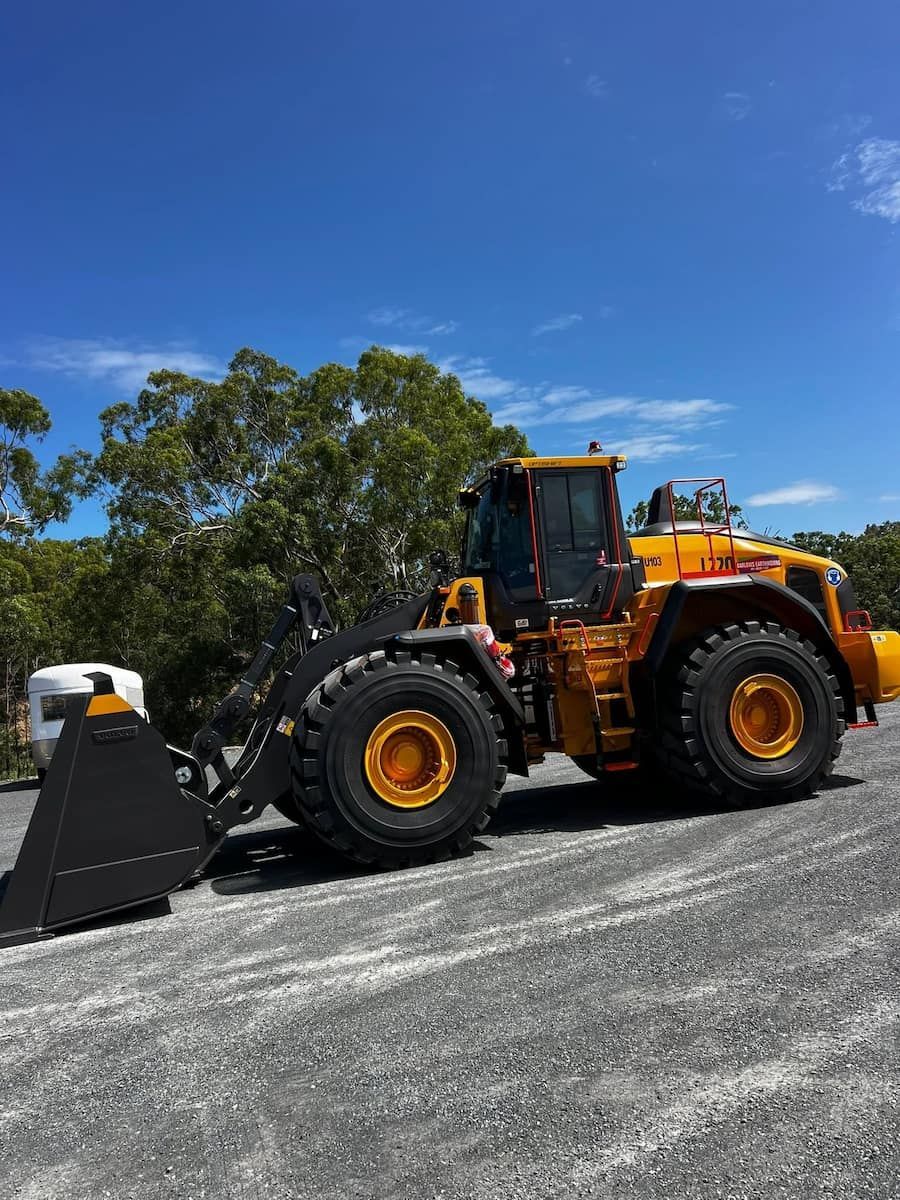Orange Front Loader Parked on a Gravel Lot Under a Blue Sky — Barlow's Earthmoving in Rockhampton, QLD