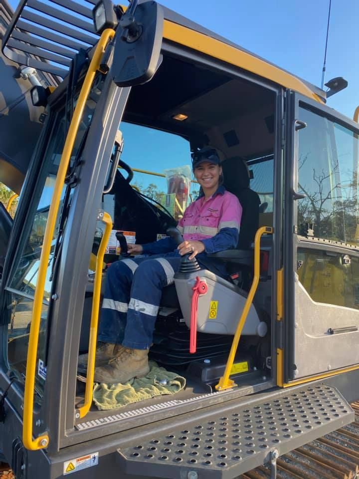 Woman Operating Heavy Machinery, Wearing Work Clothes, Smiling — Barlow's Earthmoving in Coorooman, QLD