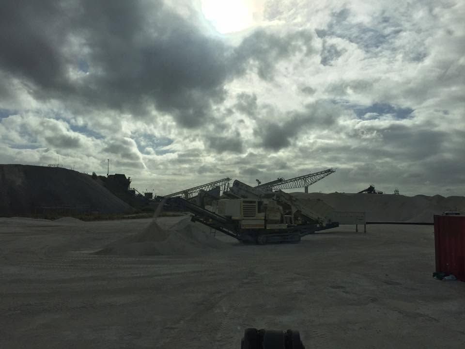 Industrial Machinery in a Gravel Lot Under a Cloudy Sky, With a Red Container — Barlow's Earthmoving in Coorooman, QLD