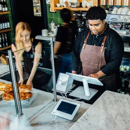 A man and a woman are working at a counter in a restaurant.