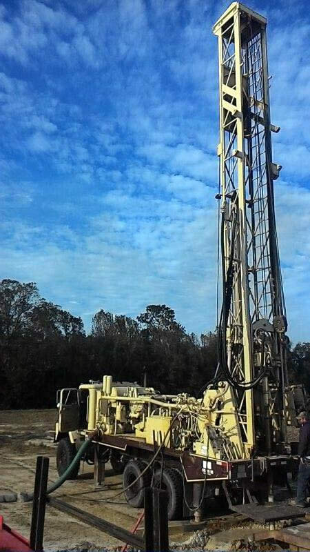 Drilling rig on a truck, outdoors under a partly cloudy sky.