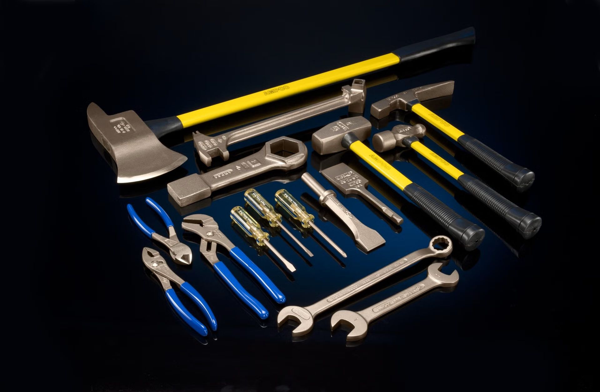 Assorted Ampco Safety Tools including hammers, wrenches, and chisels arranged on an industrial surface.