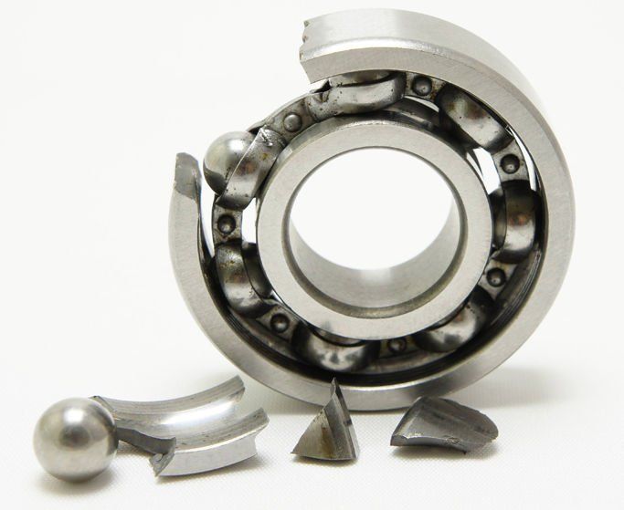 Industrial roller bearing removed from a conveyor shaft, showing wear patterns linked to premature bearing failure.