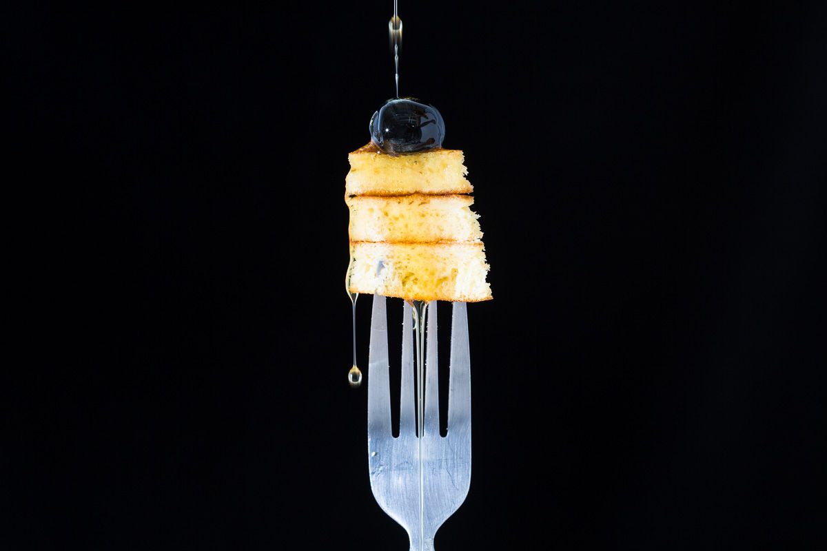 Maple syrup, blueberry and pancakes on a fork, on a black background. Food photography by JAM Creative.