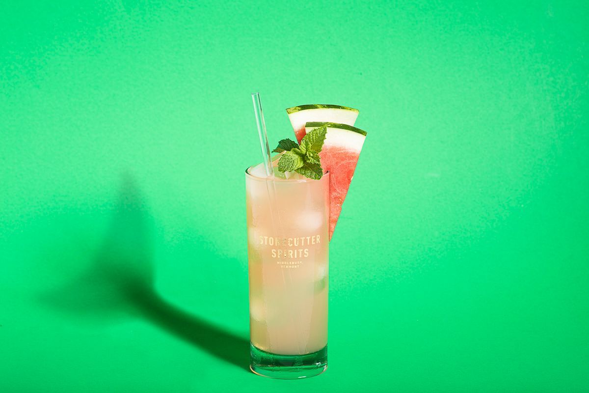 Beverage product photography of cocktail with watermelon on green paper throwing a shark tail shadow for Stonecutter Spirits.