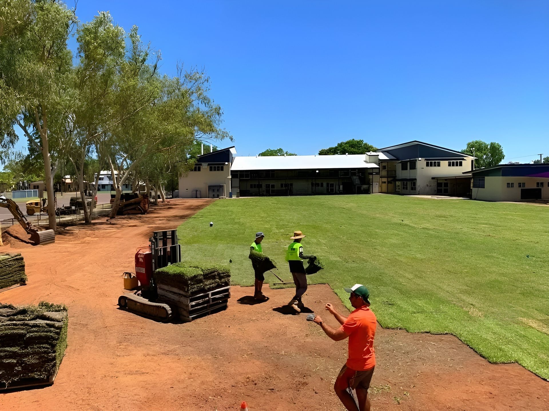 Workers Laying Sod on A Lawn with A Forklift and Building — Top Notch Turf in Rasmussen, QLD