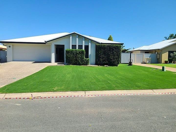 House with White Roof and Garage, Green Lawn, Blue Sky, Hedges, and Neighboring House — Top Notch Turf in Rasmussen, QLD